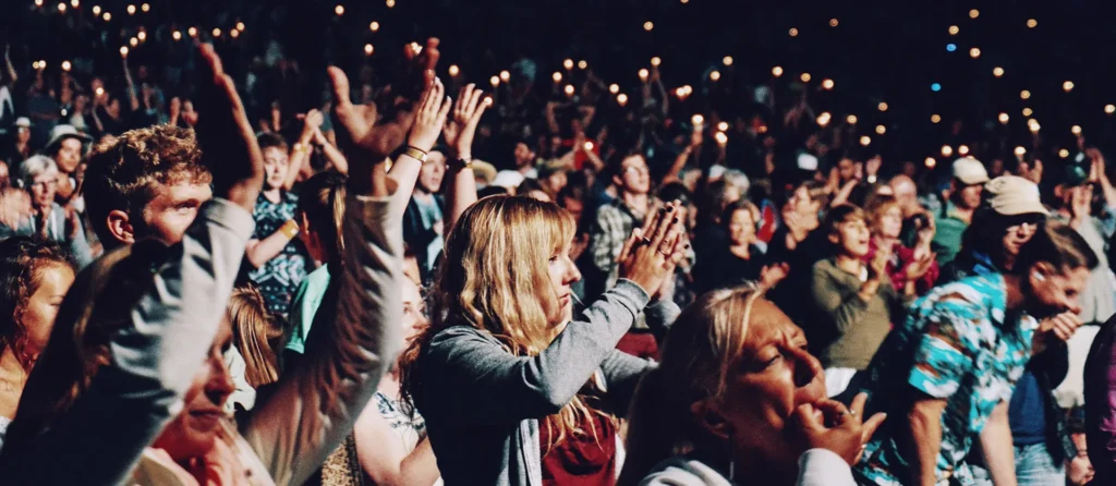A concert crowd with raised hands and phones in the air