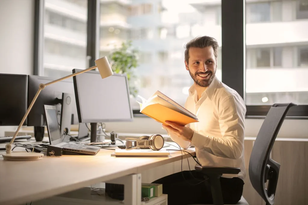 A consultant smiling at a desk, notebook in hand