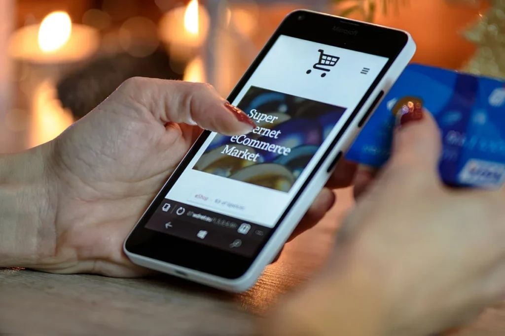 A buyer paying in a shop app on a phone, card in hand